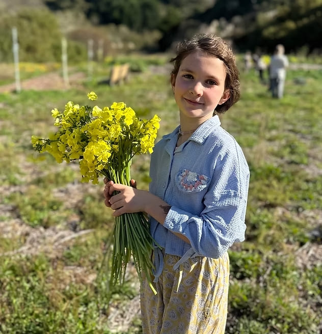 Bambina con un mazzo di fiori in mano, simbolo di un'educazione che fa fiorire il potenziale umano